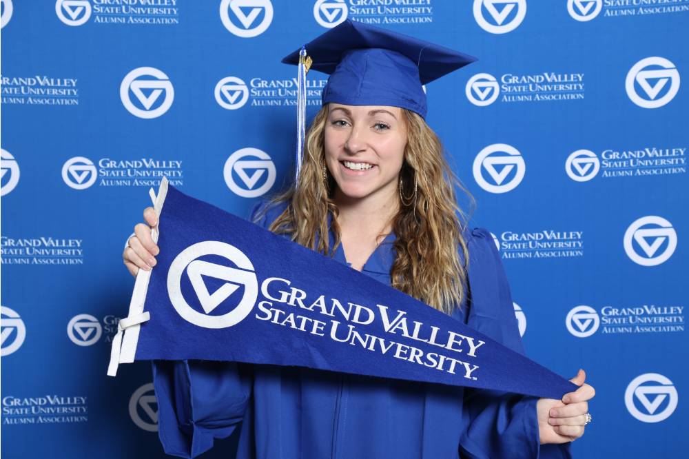 A upcoming graduate poses with GV flag at GradFest